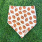 white dog bandana with footballs in front of turf