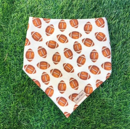white dog bandana with footballs in front of turf